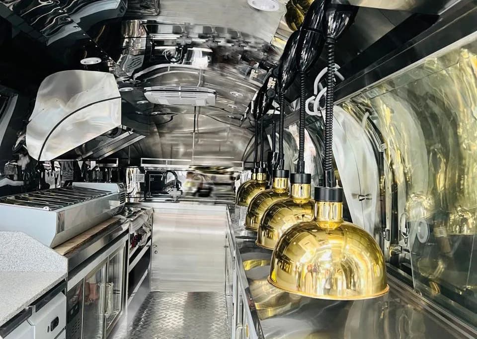 Stainless steel QH trailer interior with brass heat lamps above the service line